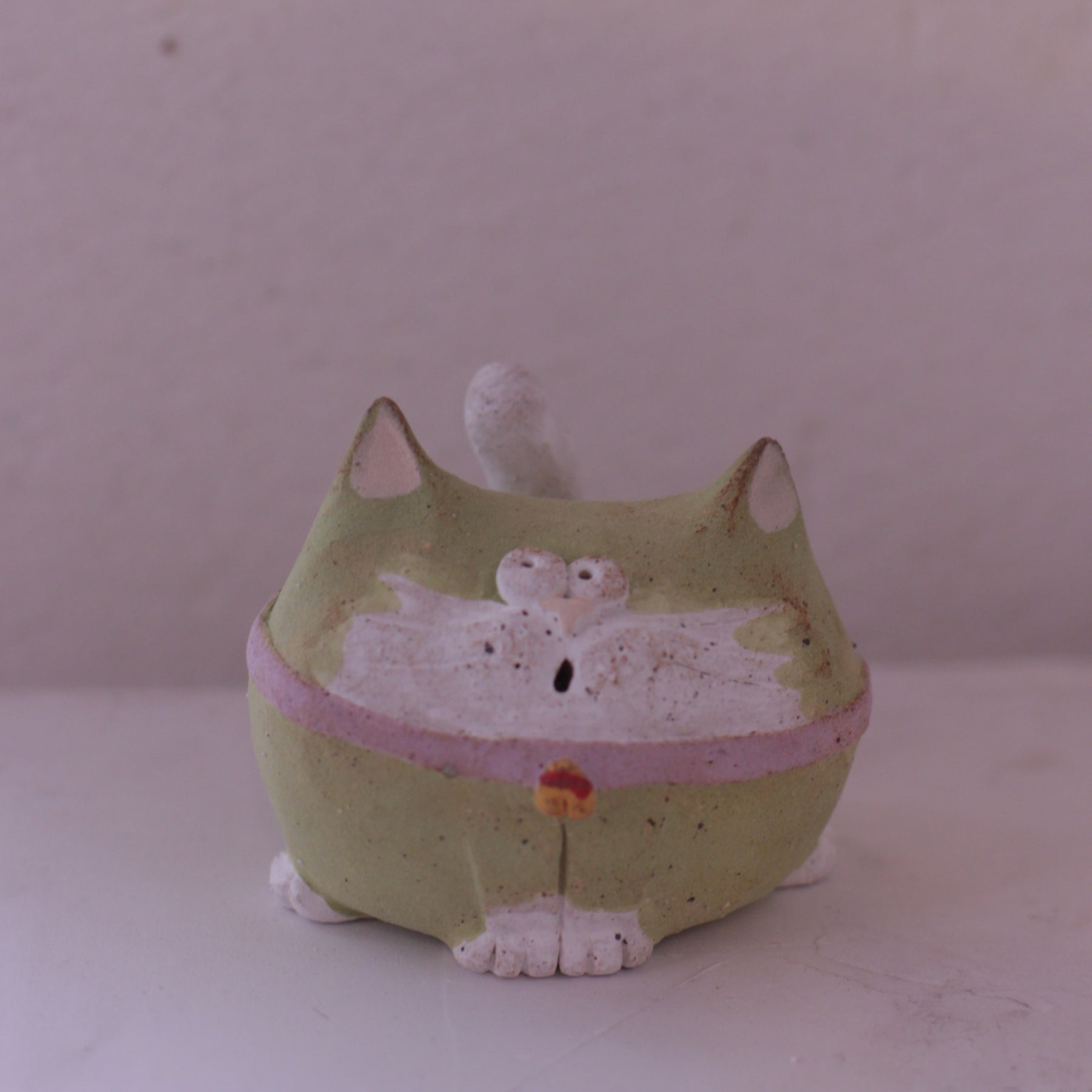 Handmade clay cat figurine pottery in green with white accents and a pink collar by various artist