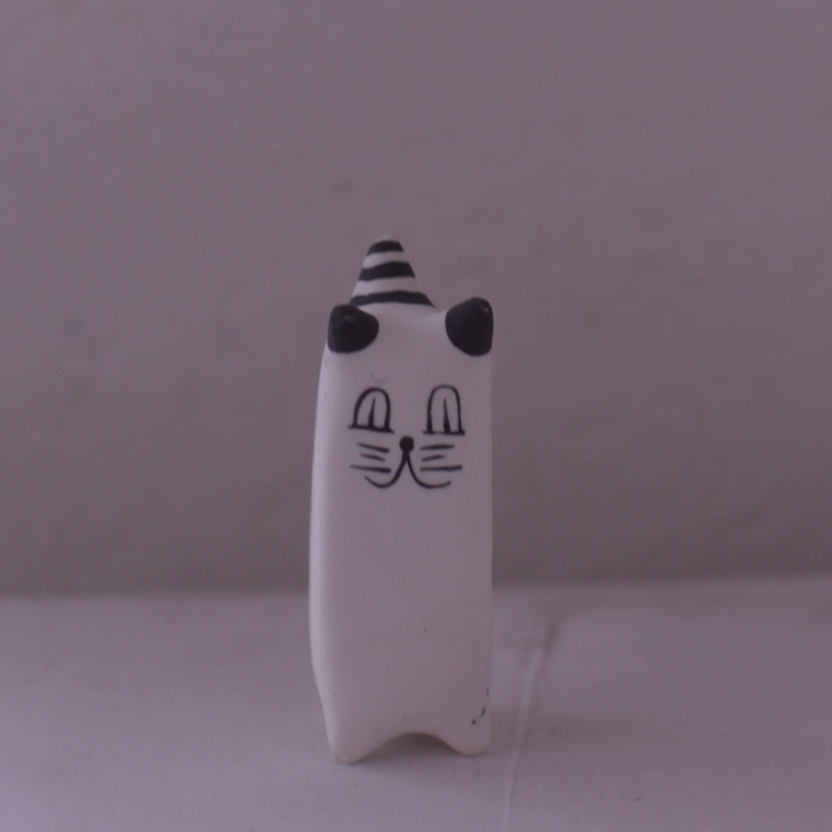Handmade clay cat figurine with black and white stripes and simple facial features by Various Artist