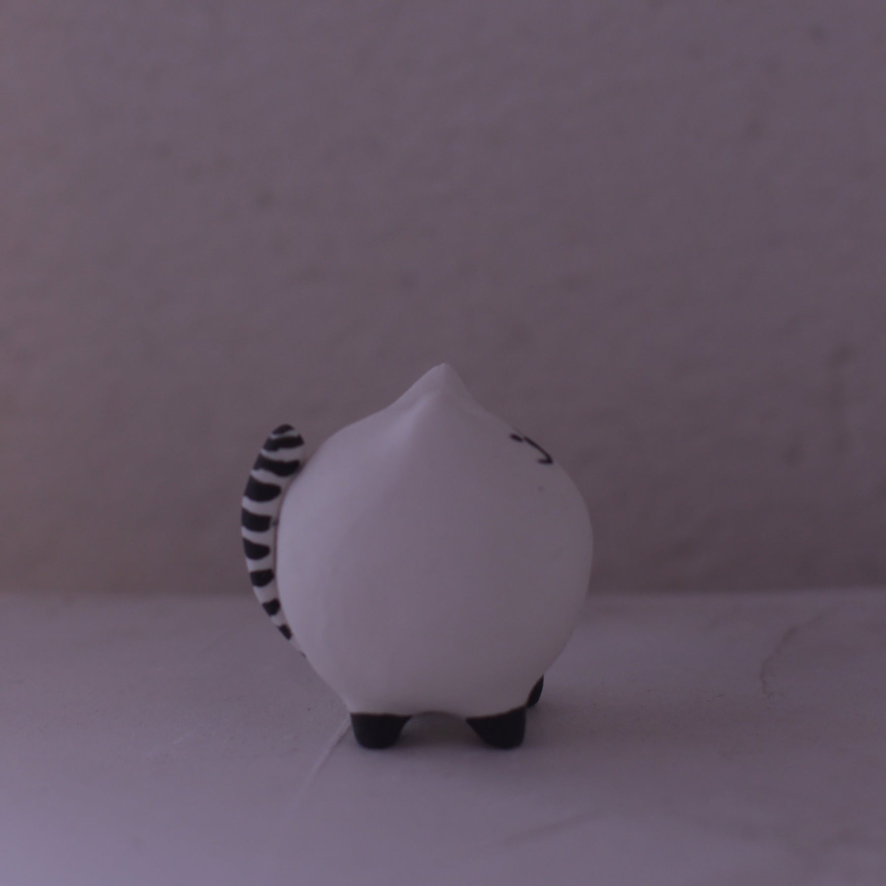 Handmade Clay Cat Figurine with black striped tail and small black feet on a neutral background