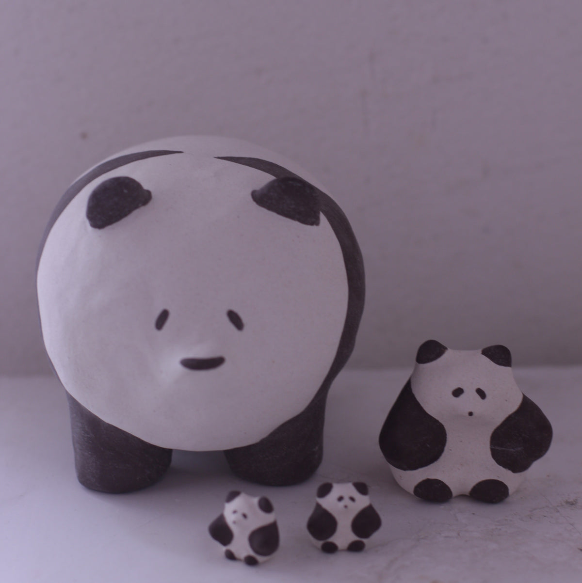 Handmade pottery panda animal figurine set with one large and three small black and white pandas
