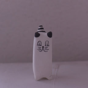 Handmade clay cat figurine with black and white stripes and simple facial features by Various Artist
