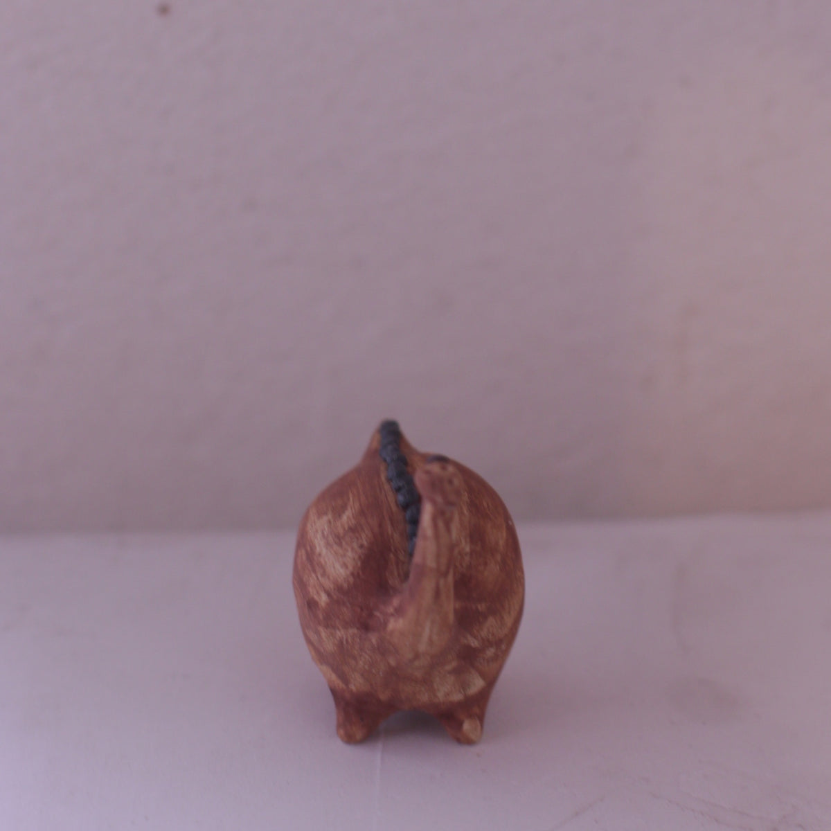 Handmade pottery animal figurine shaped like a brown pig with a curled tail