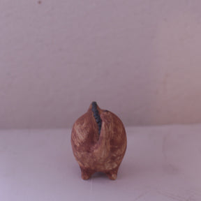 Handmade pottery animal figurine shaped like a brown pig with a curled tail