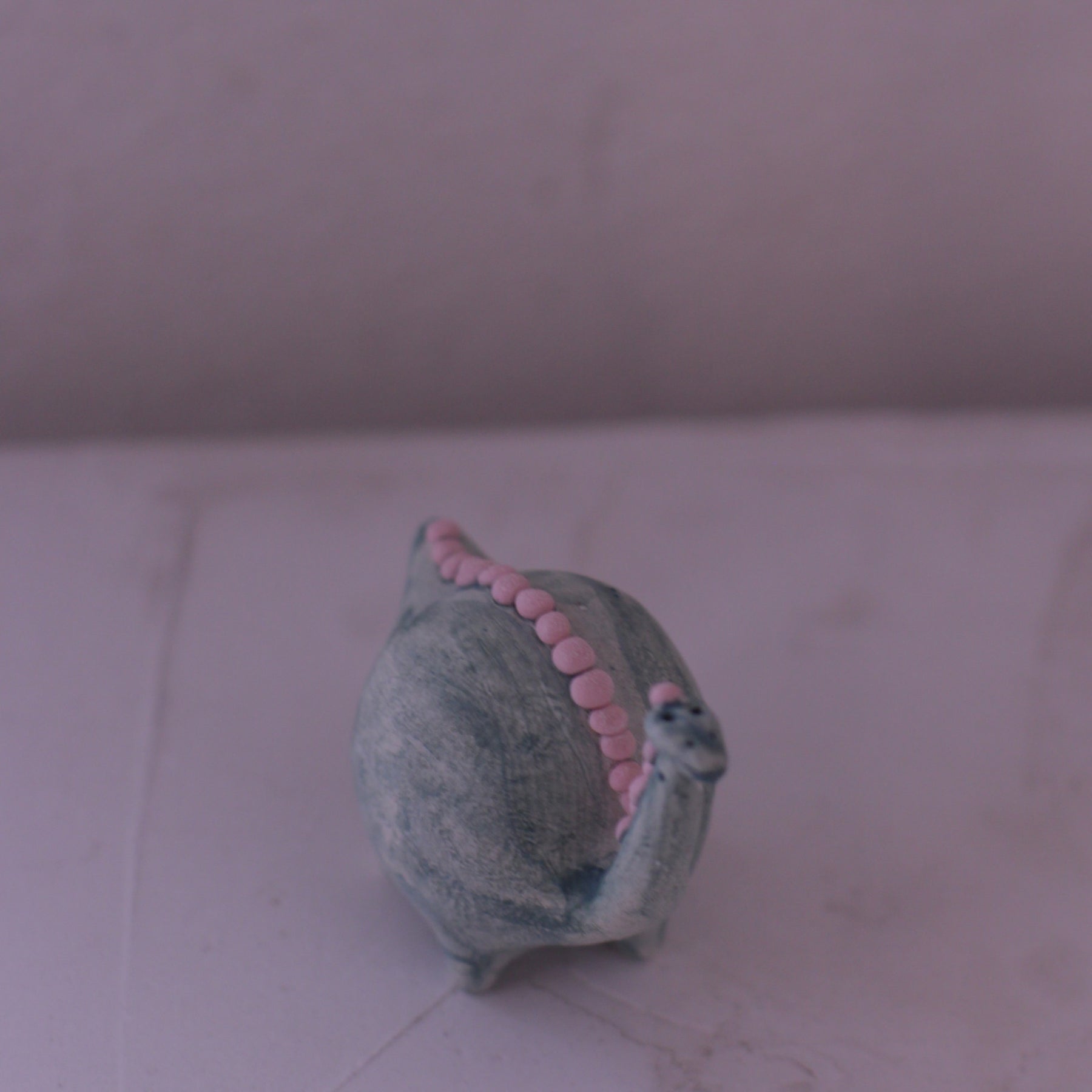 Handmade pottery animal figurine shaped like a snail with pink accents on its shell
