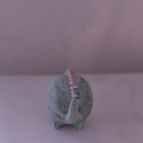 Handmade pottery animal figurine of a dinosaur with a gray body and pink dots along its back