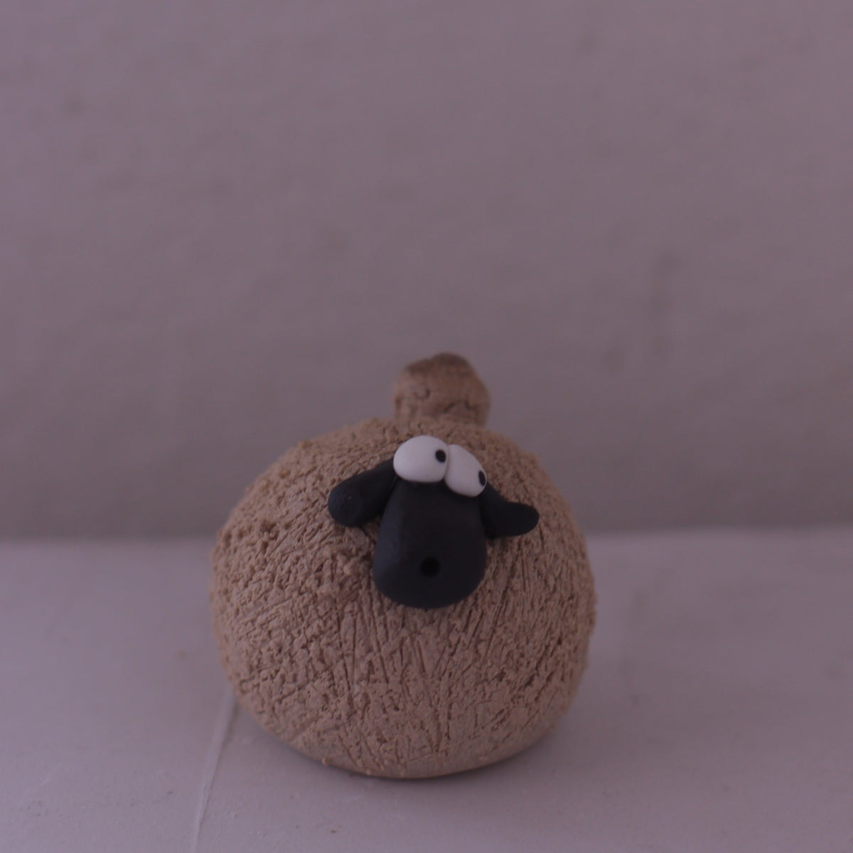 Handmade pottery animal figurine of a round sheep with textured body and black face