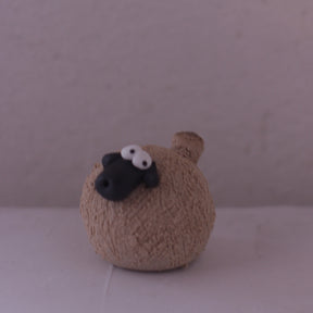 Handmade pottery animal figurine of a round sheep with textured beige body and black face