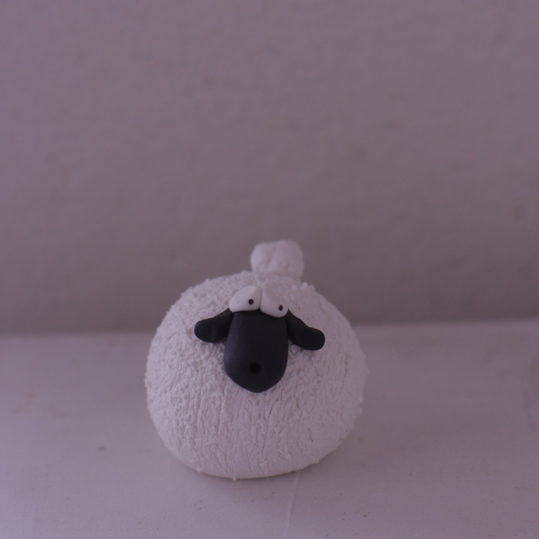 Handmade pottery sheep figurine with textured white body and black face by various artist front view